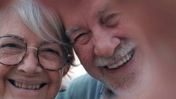 特写肖像幸福真诚的中年老年退休家庭夫妇用手指做心形手势一起在户外表达爱或表达真挚的感情看着镜头