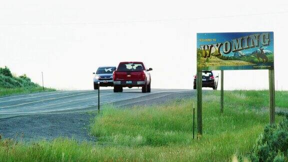 在日落时分车辆驶过怀俄明州科罗拉多州边界上的怀俄明州州界线标志