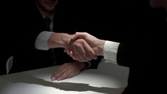 商业伙伴在黑暗的阴影中握手