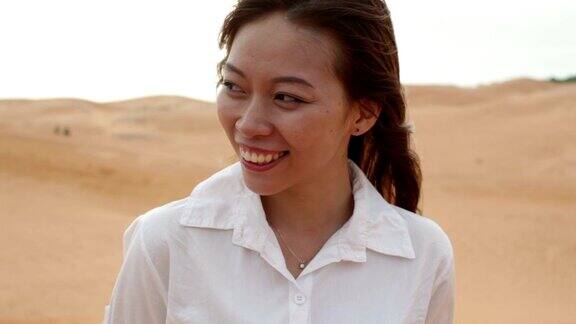 亚洲女人微笑户外沙漠风吹头发