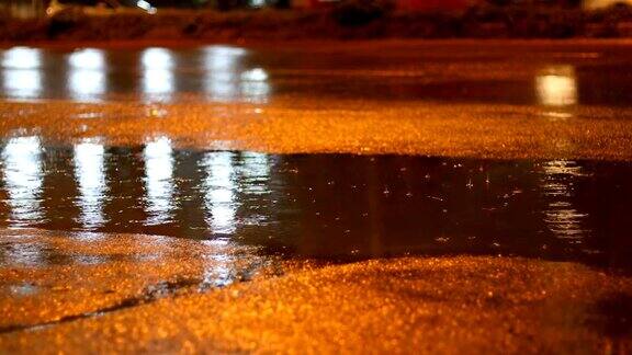 夜晚的街道在雨天的白天雨水滴在水坑里汽车行驶在柏油路上