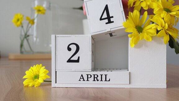 春月四月二十四日一个女人的手翻动着一本立体日历白色的万年历在黄花旁边的桌子上一个月后更改日期每个月的每一天数量