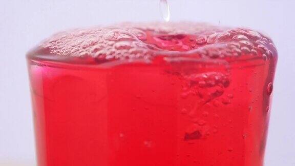 红色的软饮料在杯子里冒泡