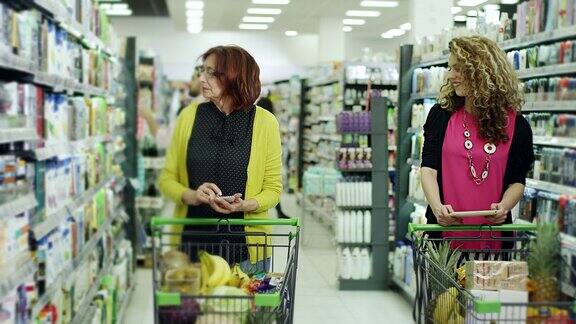 年轻女性帮助老年女性使用平板电脑在超市购物