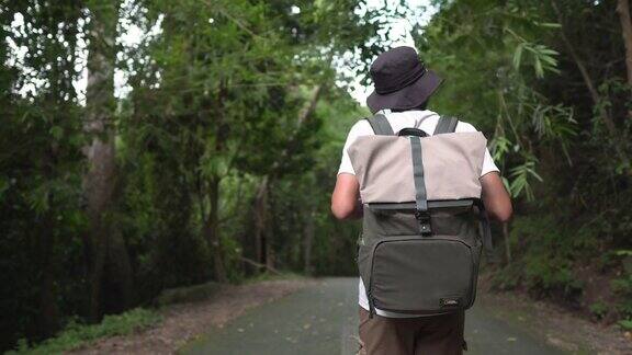 一名男性旅行者背着背包走在乡间小路上