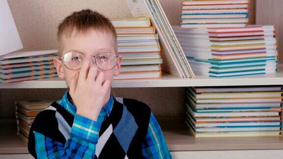 疲惫的七岁男孩戴着眼镜坐在地板上的书中