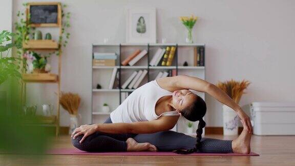 平静的迷人的亚洲女人练习瑜伽侧身伸展的姿势在卧室里冥想早上醒来后感觉如此舒适和放松保健理念