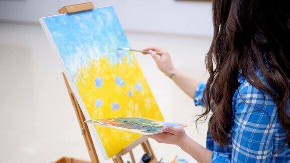 女孩在画布上画着蓝色的花朵