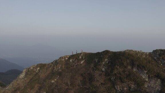 无人机拍摄的日落时分一群徒步旅行者沿着山脊徒步旅行