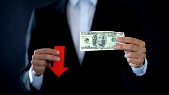 商人展示美元钞票和红色箭头标志下跌金融危机