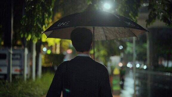 在潮湿的天气里撑伞行走的自由职业者晚上过马路