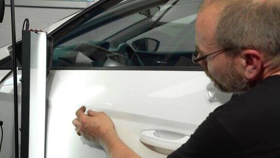 汽车修理店左车门表面凹痕修复视频流程技术员正在使用工具进行无漆凹痕修复