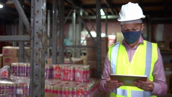 仓库工作人员戴口罩和防护服在仓库使用平板电脑检查产品