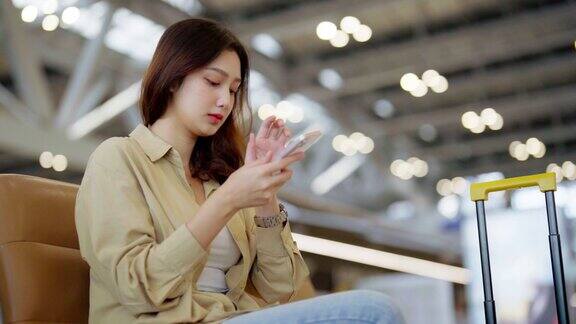 亚洲妇女在机场等待离开假期假期亚洲女乘客坐在候机大厅用手机等机