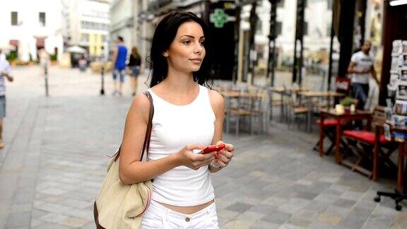 漂亮的女孩拿着手机在街上