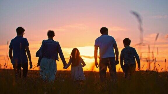 日落时分一家人带着三个孩子在草地上散步