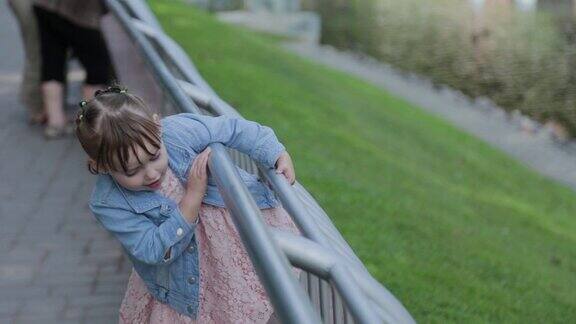 快乐的小女孩从公园的栏杆旁走过