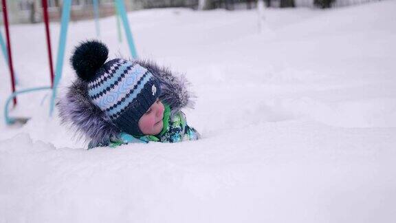 一个小孩在冬天的公园里玩雪躺在白雪上微笑的婴儿新鲜的空气里充满了乐趣和游戏