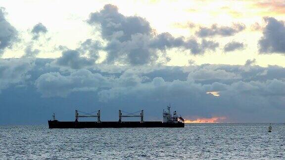 日出时货船在平静的海面上出现剪影
