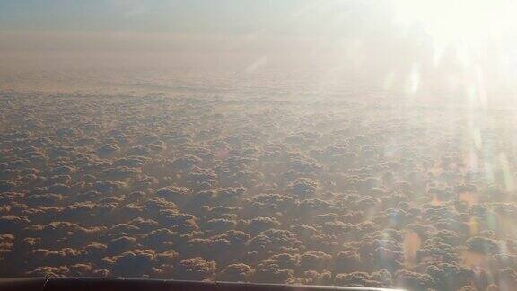 全景鸟瞰图从飞机飞行在白色蓬松的云在日出日落