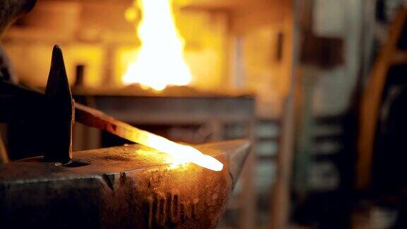 铁匠从炉子里取出金属用锤子敲打特写镜头