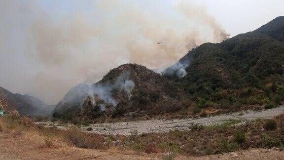 加州大火的4K视频天空起重机和贝尔直升机往火中洒水