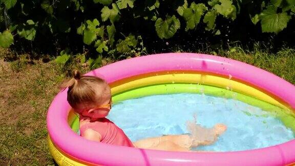 一个孩子在一个小小的充气儿童游泳池里泼水