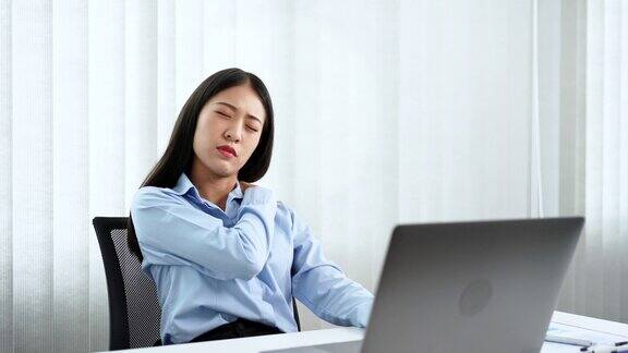 年轻的亚洲商务女性在办公室用笔记本电脑努力工作因为颈部疼痛而做伸展运动热身和锻炼的4k视频片段