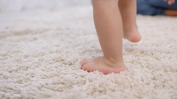 蹒跚学步的孩子在地毯上向妈妈走来
