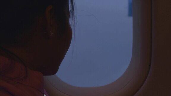 一名亚洲女子向飞机窗外望去