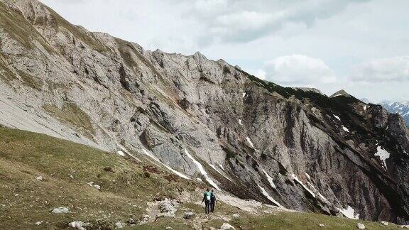 这是一对夫妇在奥地利阿尔卑斯山锡纳贝尔地区徒步旅行的全景无人机拍摄山坡上仍有部分被雪覆盖着多石和尖锐的山有点阴天探索自然