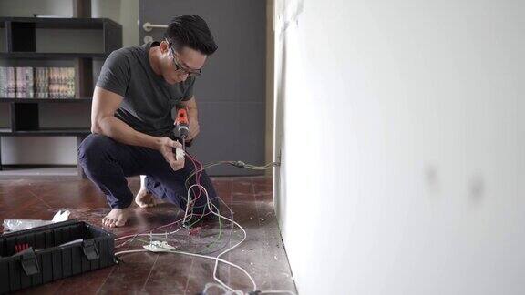 亚洲华人男性电工连接插座到电线将电线安装到插头上