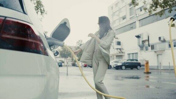 一位年轻女子在雨中跳舞她的电动汽车正在充电