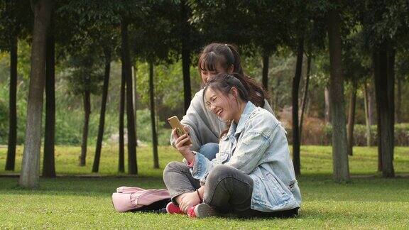 两个亚洲女大学生在校园里使用手机