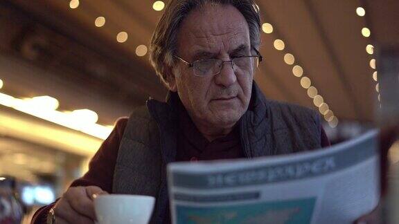 老人花时间在外面看报纸喝咖啡