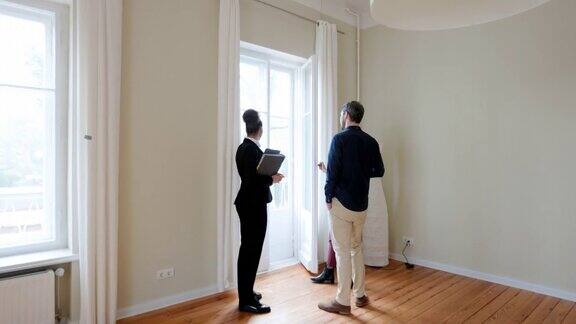 一位女性房地产经纪人在给一对夫妇介绍一套公寓