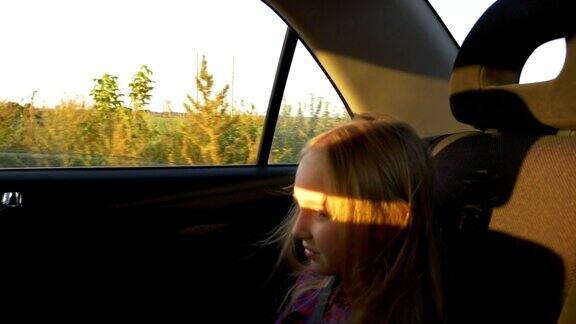 一个非常伤心的年轻白人女孩坐在靠近窗户的车后座上风吹散她的头发阳光照在脸上女孩哭了