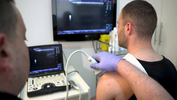 一名男性骨科医生在诊所给这名青少年患者做肩部超声检查