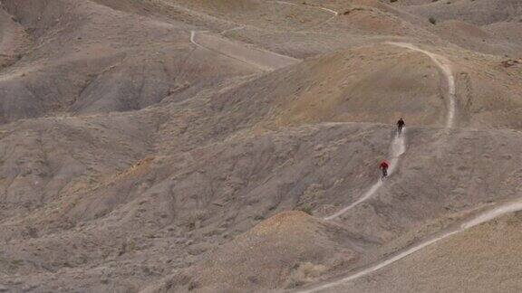 远处的山地自行车手沿着沙漠小径骑行
