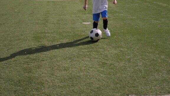 一个小男孩在足球场上训练练习运球和假动作