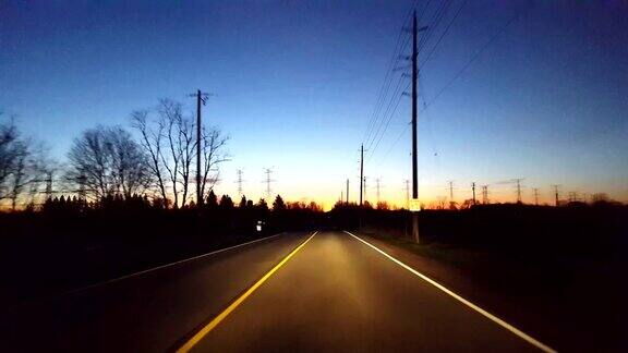在日出时驾驶乡村道路清晨太阳从地平线升起时司机的视角