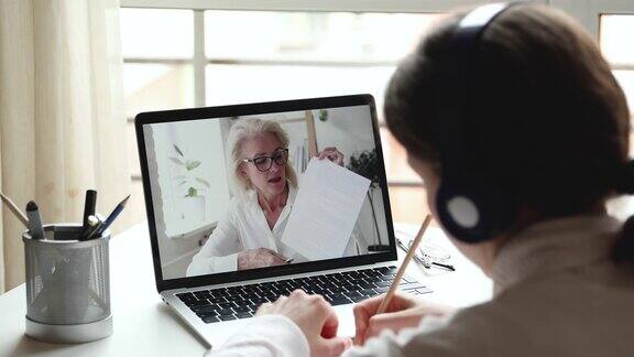 年长的女性在线教师在笔记本电脑屏幕上进行远程教学