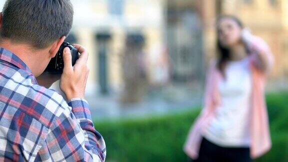一名年轻男子在户外为摆姿势的女子拍照摄影自由职业