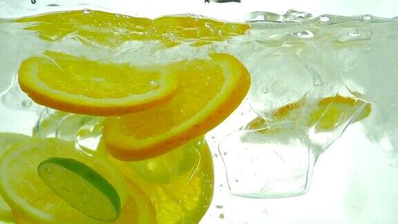酸橙、柠檬和橙子片滴在冰水里关闭了缓慢的运动
