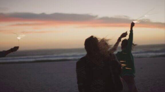 朋友们在海滩上拿着烟花跳舞
