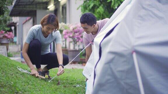 一对亚洲华人夫妇在自家后院搭起帐篷露营进行周末度假活动