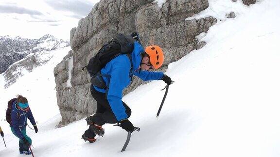 冬季登山运动员用冰斧爬上一座雪山