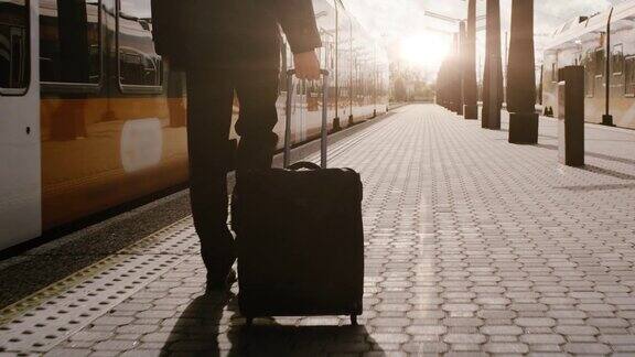 日落时分自信的男人带着行李走在火车站上