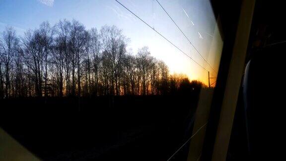 美丽的日落天空之间的树木从移动的火车窗口体贴的心情和怀旧慢动作