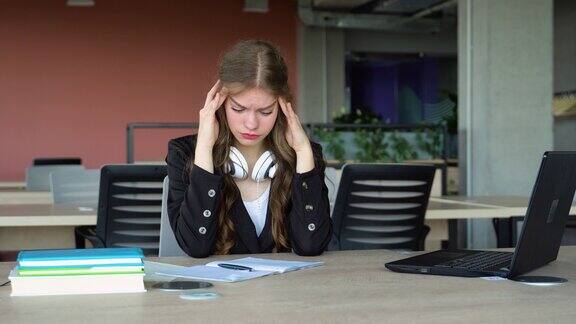 焦虑的女孩在学校学习时感到疲倦大学生在课堂上头痛困扰和压力的女孩做不知道答案的考试